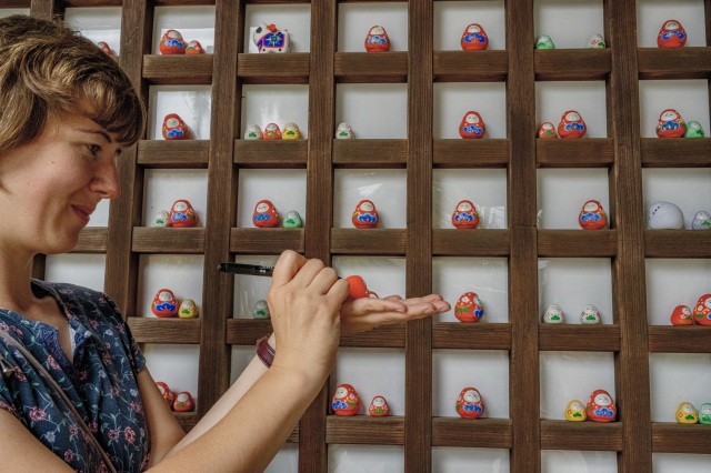 Writing a wish on the Kaga Hachiman Okiagari and offering it to the shrine, connecting personal hopes with Shinto tradition.
